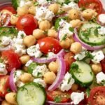 A colorful Mediterranean Chickpea Salad with cucumbers, tomatoes, and feta in a large bowl