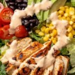 A colorful Southwest chicken taco salad in a bowl with grilled chicken, avocado, and creamy dressing