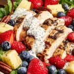 A vibrant bowl of High Protein Strawberry Poppyseed Salad with grilled chicken, fresh strawberries, and creamy dressing