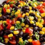 A colorful bowl of black bean salad with corn, red peppers, and avocado