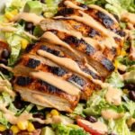 A colorful chopped salad with grilled chicken, black beans, corn, and BBQ ranch dressing in a white bowl.