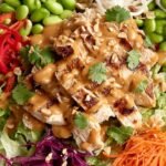 A colorful bowl of Thai Peanut Chicken Salad with shredded cabbage, carrots, and peanut dressing.