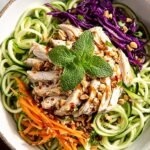 A colorful bowl of Vietnamese Chicken Zoodle Salad topped with fresh herbs and crushed peanuts.