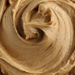 Creamy protein peanut butter frosting swirled in a bowl with a spoon