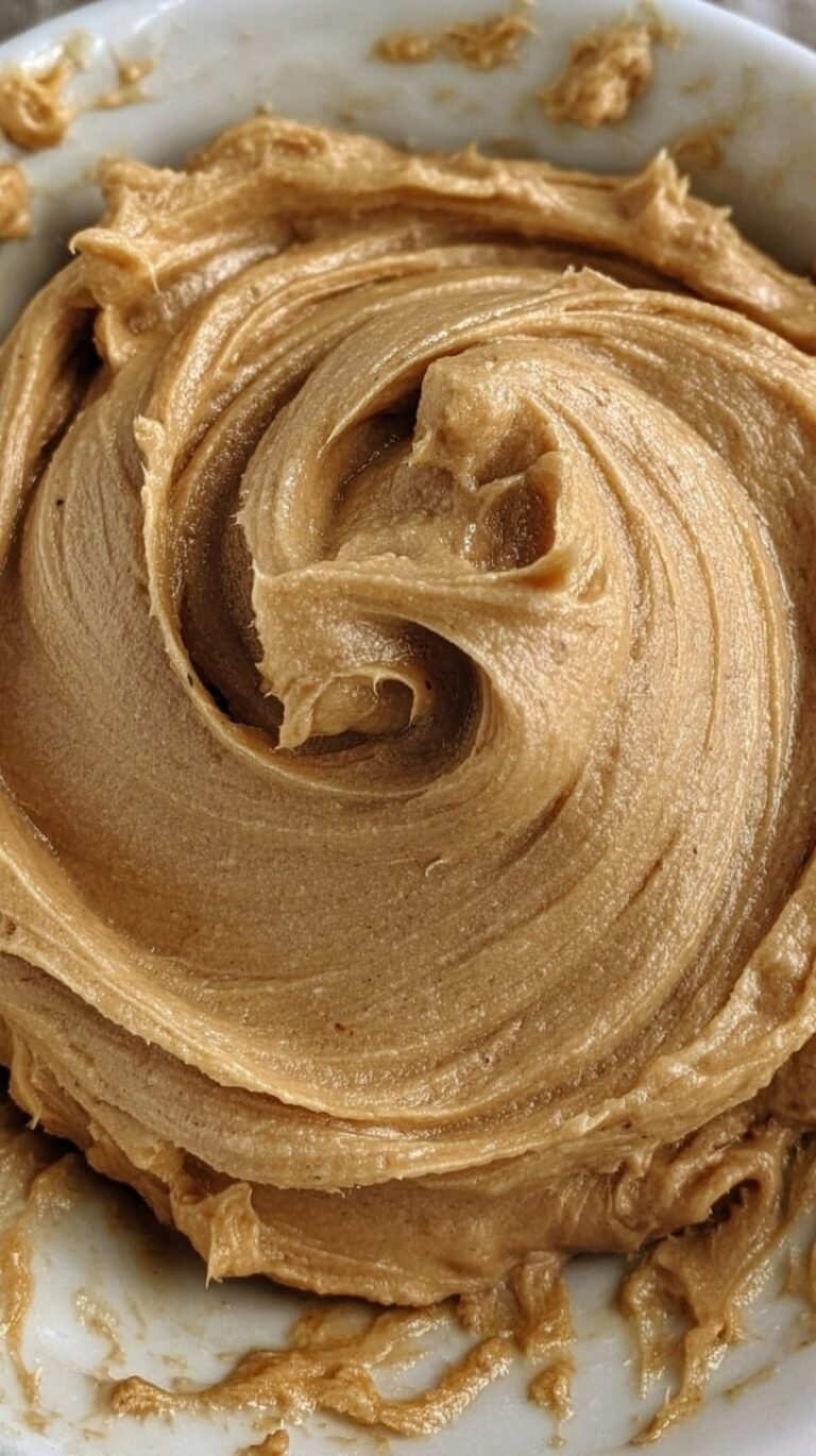 Creamy protein peanut butter frosting swirled in a bowl with a spoon