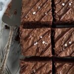 A stack of fudgy flourless black bean brownies with chocolate chips on top