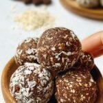 Uniform dark chocolate protein balls arranged on a white plate