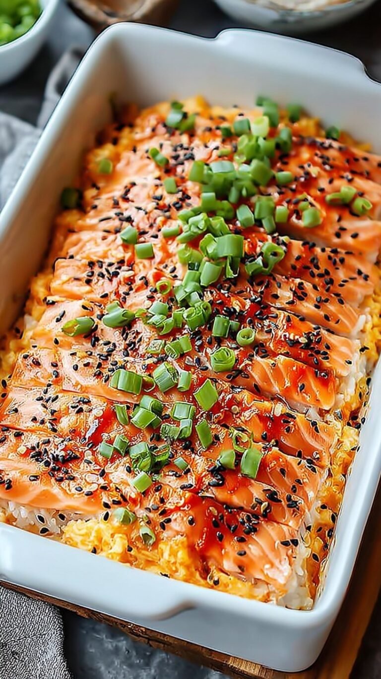 A golden-brown salmon sushi bake in a glass dish topped with green onions and sesame seeds