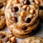A stack of golden brown butterscotch chocolate chip cookies with melted chocolate and flaky sea salt on top.