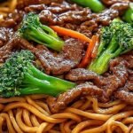 A steaming bowl of beef lo mein with colorful vegetables and tender steak strips