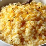 A bowl of golden creamy cheesy rice garnished with fresh green parsley