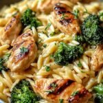 A skillet filled with creamy cheesy chicken broccoli orzo and melted cheddar cheese