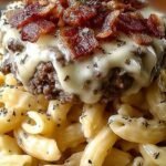 A bowl of creamy penne pasta with ground beef, crispy bacon, and melted cheese garnish.