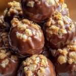 A tray of chocolate-covered Butterfinger dessert balls topped with candy crumbs