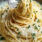 A bowl of creamy fettuccine pasta coated in garlic parmesan sauce and topped with fresh parsley.