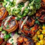 A vibrant grilled shrimp bowl with sliced avocado, corn salsa, and creamy chipotle sauce over white rice.