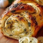 A golden brown loaf of swirled garlic herb and cheese bread on a wire rack