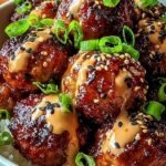 A plate of glazed Korean BBQ meatballs topped with scallions and sesame seeds