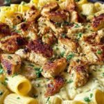A bowl of rigatoni pasta with Cajun chicken and creamy alfredo sauce topped with parsley