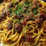 A bowl of creamy Cajun beef spaghetti topped with fresh parsley and melted cheese