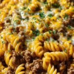 A close up shot of cheesy rotini pasta with ground beef in a garlic butter sauce