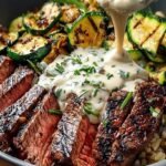 A colorful grilled steak bowl with charred zucchini and creamy sauce over white rice.