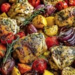 A sheet pan filled with roasted herb chicken, broccoli, red peppers, and zucchini garnished with parmesan.