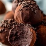 A plate of dusted chocolate protein truffles on a marble countertop