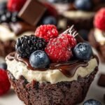 Two glass cups filled with creamy chocolate mousse and topped with fresh raspberries and blueberries.
