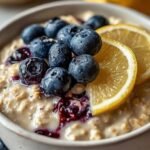 A mason jar filled with creamy lemon blueberry protein overnight oats topped with fresh berries