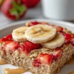 A warm ramekin of strawberry banana baked oats topped with fresh berries