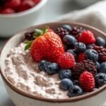 A fresh cottage cheese bowl topped with blueberries, strawberries, chia seeds, and sliced almonds.