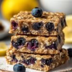 Golden brown protein blueberry snack bars sliced into squares in a baking pan