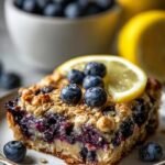 A golden-brown ramekin of baked oats filled with fresh blueberries and lemon zest.
