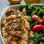 Roasted lemon garlic chicken cubes and broccoli florets served over brown rice in glass meal prep containers.