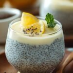 A glass jar filled with creamy lemon chia pudding topped with fresh lemon zest and a sprig of mint.