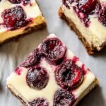 A square cranberry cheesecake bar with a vibrant red swirl on a white plate