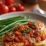 Pan-seared chicken cutlets simmering in a fresh tomato marinara sauce with green basil garnish.
