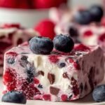 A tray of frozen yogurt bars topped with fresh strawberries, blueberries, and granola