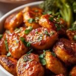 Four glass meal prep containers filled with seasoned cubed chicken, steamed broccoli, and white rice on a clean kitchen counter.