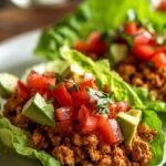 A platter of fresh butter lettuce leaves filled with savory ground turkey and topped with shredded carrots.