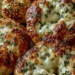 Golden brown mini bagel bites topped with melted cheese and pepperoni on a baking sheet.