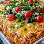 A cheesy chicken enchilada rice casserole in a baking dish with melted cheese and corn.