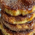 A stack of cinnamon-sugar coated pancakes drizzled with dark chocolate ganache on a white plate.