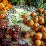 A vibrant bowl with roasted sweet potatoes, crispy chickpeas, quinoa, and creamy tahini dressing.