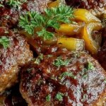 Golden seared beef patties smothered in creamy mushroom gravy in a baking dish