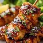 Glazed honey garlic chicken skewers garnished with sesame seeds and green onions in an air fryer basket