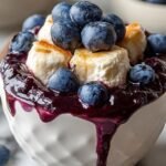 A creamy whipped cottage cheese bowl topped with fresh blueberries, honey, and sliced almonds.