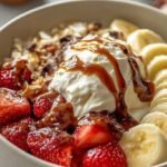 A colorful cottage cheese banana split bowl topped with strawberries, pineapple, walnuts, and chocolate chips.