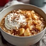 A white bowl filled with creamy cottage cheese topped with diced red apples, cinnamon, and chopped walnuts.